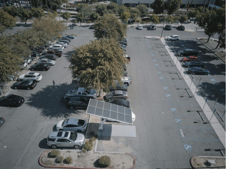 Aerial view of a solar-powered electric vehicle (EV) charging station in a parking lot, showcasing sustainable energy solutions for transportation.
