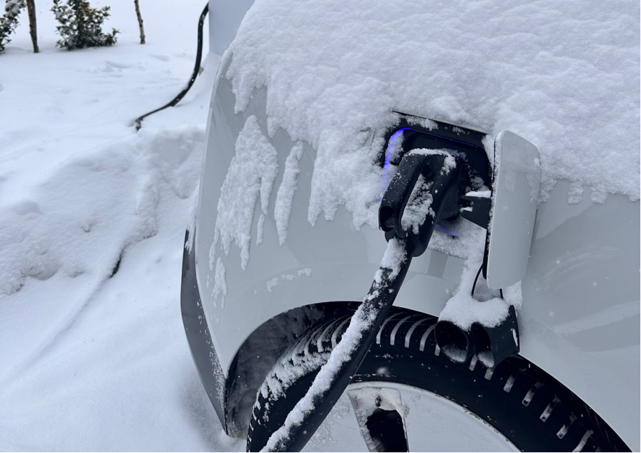 Electric vehicle plugged in with a Pilot x Piwin AC EV charger during a snowy day, demonstrating the charger's durability in winter conditions.