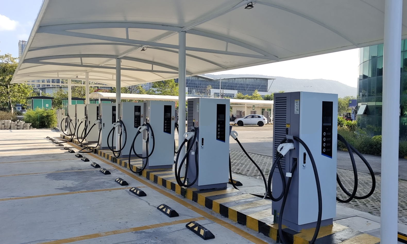 Covered electric vehicle charging station with multiple charging units in an outdoor setting.