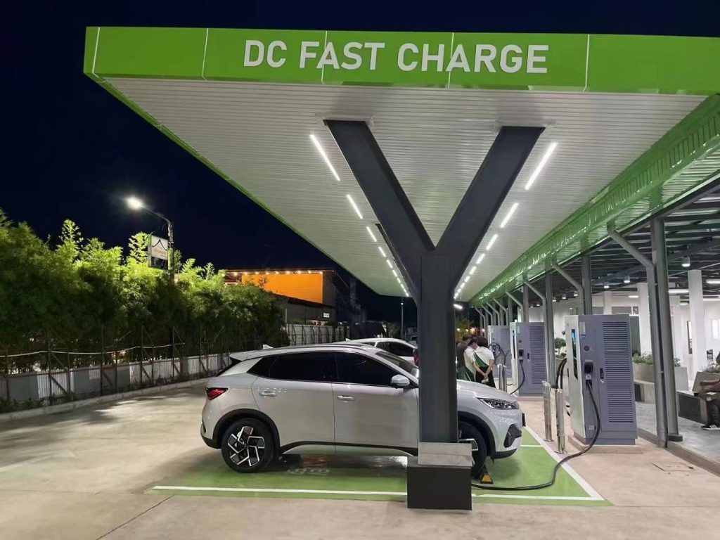 Electric vehicles charging at a DC fast charge station at night