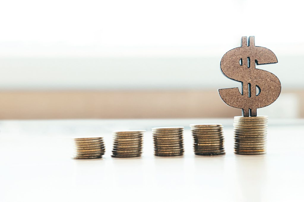 On the table are different numbers of coins, increasing from left to right, with the dollar sign on the rightmost coin.