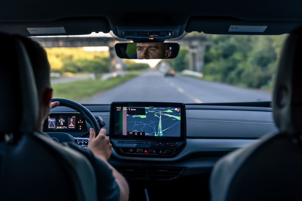 A man is driving an electric car on the highway.