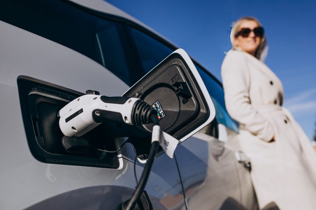 A woman stands next to an electric car.